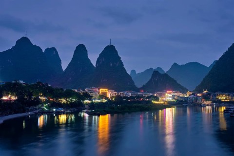 View of Yangshuo town illuminated in the evening with dramatic karst mountain landscape in