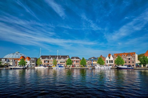 Boats and houses on Spaarne river with blue sky. Haarlem, Netherlands