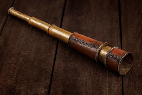 Vintage retro spyglass on wooden background