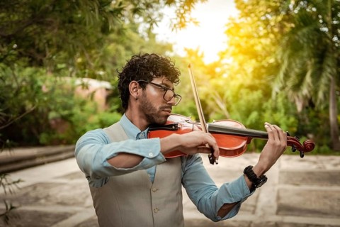 Portrait of man playing violin at sunset. Close up of violinist man playing in the street.