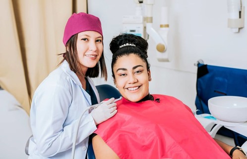 Female dentist with smiling female patient looking at camera, Professional dentist with female