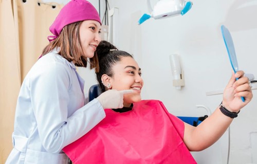 Female patient checking teeth after curing teeth in dental clinic. Dentist with satisfied patient