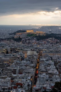 View over the sea of houses of Athens, illuminated Parthenon temple on the Acropolis, from Mount