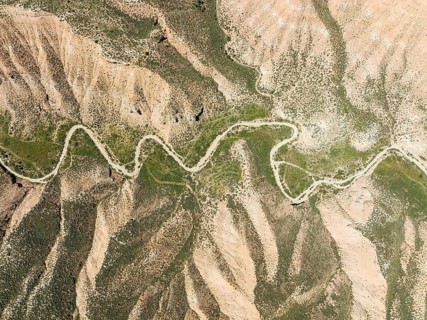 Dirt road in the Gorafe Desert with green surroundings after some rainfalls, aerial view, drone