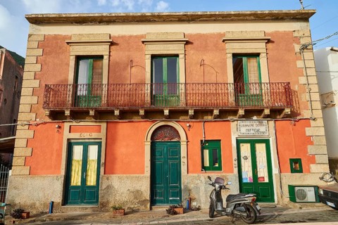 Old house, old rose-coloured façade, green windows and doors, balcony, scooter, Malfa, Salina,