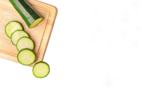 Courgettes (Cucurbita pepo), cut open, on wooden board, on white, copy room
