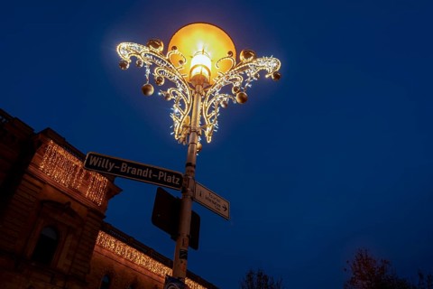 Christmas decorated street lamp on Willy-Brandt-Platz, behind it central station, Magdeburg,
