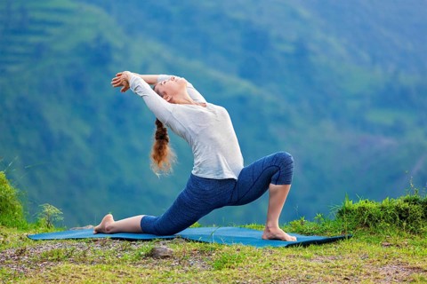 Yoga outdoors, sporty fit woman practices Hatha yoga asana Anjaneyasana, low crescent lunge pose