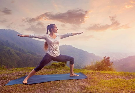 Yoga outdoors, sporty fit woman doing Ashtanga Vinyasa Yoga asana Virabhadrasana 2 Warrior pose