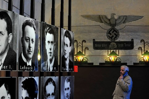 Visitors with audio guide looking at pictures of prisoners at Fort Breendonk, Belgium, Europe