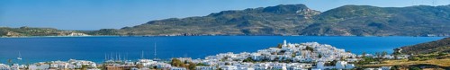 Panorama of Plaka village with traditional Greek church white painted Greek houses and ocean coast.