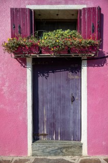 Front door and window with flowers and pink shutters, detail of a house facade, colourful houses on