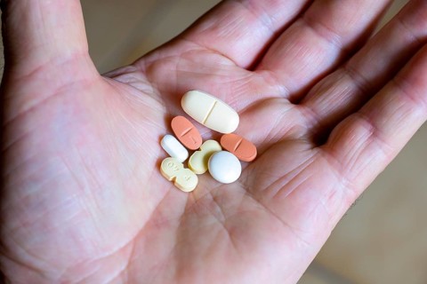 Hand holding various tablets, medicines, drugs