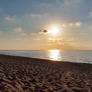 Sunbeams in a slightly cloudy sky, sunset by the sea, deserted sandy beach in autumn, Spiaggia di
