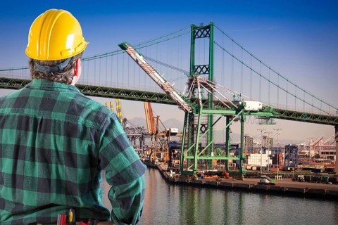 Male worker wearing yellow hard hat overlooking the san pedro ship yard and bridge