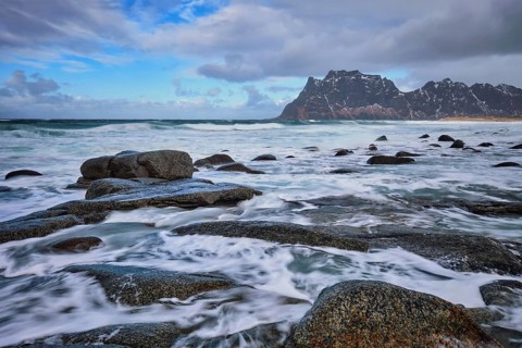 Rocks on beach of fjord of Norwegian sea in winter with snow. Utakliev beach, Lofoten islands,