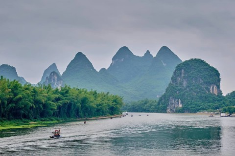 Tourist boats on Li river with dramatic karst mountain landscape in the background. Yangshuo,