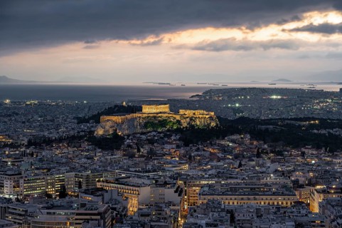 View over the sea of houses of Athens, illuminated Parthenon temple on the Acropolis, from Mount