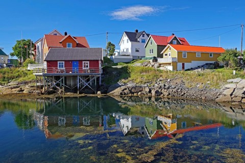 Different coloured hozhouses reflected in crystal clear sea water, Rorbuer, Henningsvaer, Lofoten,