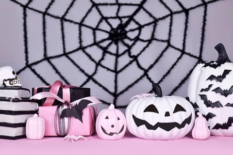 Pink and white Halloween decor with black and white pumpkins, witch hat and spell books on gray