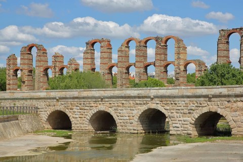 Roman stone arch bridge Puente Romano de la Puerta over the Rio Albarregas and aqueduct Acueducto