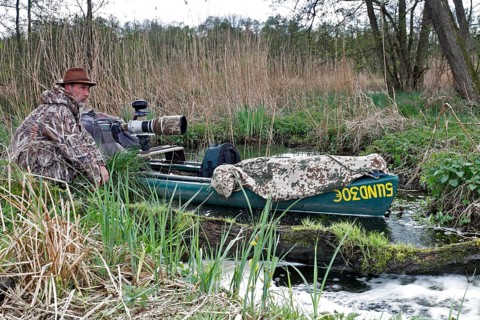 A canoe with camouflaged camera in a swamp, surrounded by vegetation and quiet nature, boat of a