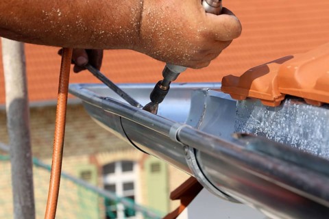 Roofer doing tinsmith work on a gutter