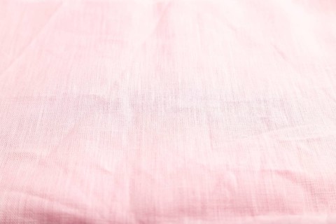 Fragment of smooth pink linen tissue. Side view, natural textile background and texture
