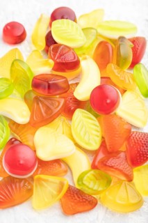 Various fruit jelly candies on gray concrete background. side view, close up