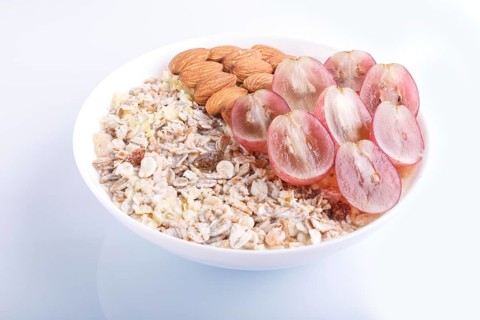 A plate with muesli, almonds, pink grapes isolated on a white background. close up
