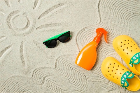 Drawing on the sand, sun and waves, sunglasses, with an orange bottle, yellow rubber slippers, sun
