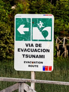 Signpost showing evacuation route in case of a tsunami, Caleta Tortel, Aysen region, Patagonia,