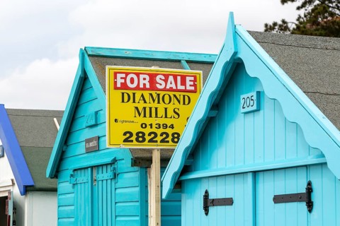 Estate agent for sale sign on seaside beach hut building, Felixstowe, Suffolk, England, UK