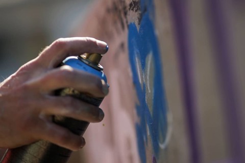 A man sprays graffiti on a wall with a spray can. Berlin, 14.08.2024