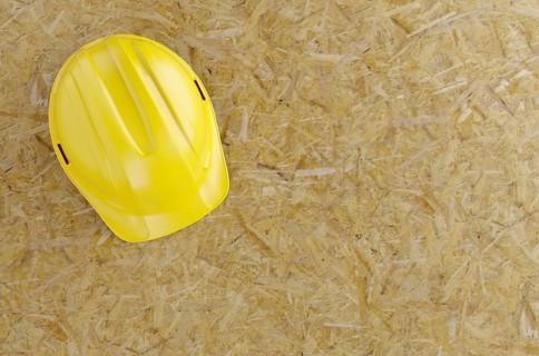 Overhead of yellow hard hat on particleboard with room for text