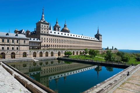 Historic monastery with reflection in the water trough under a blue sky, Real Sitio de San Lorenzo