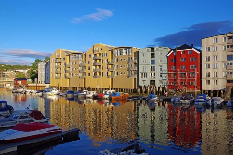 Wooden houses on the waterfront in the evening light with reflections and boats, harbour scene