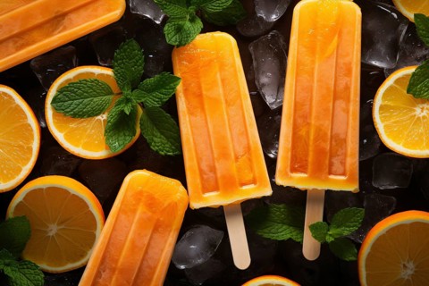 Orange ice popsicles surrounded by orange fuit slices. KI generiert, generiert AI generated