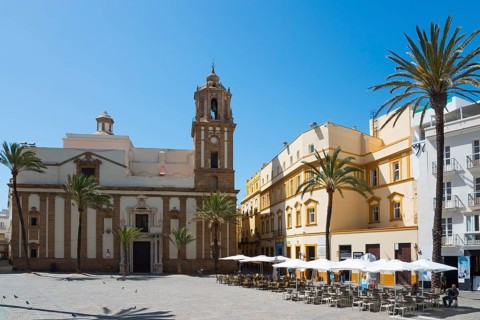 Historic cathedral on a sunny square with palm trees and blue sky, Iglesia de Santiago Apóstol,