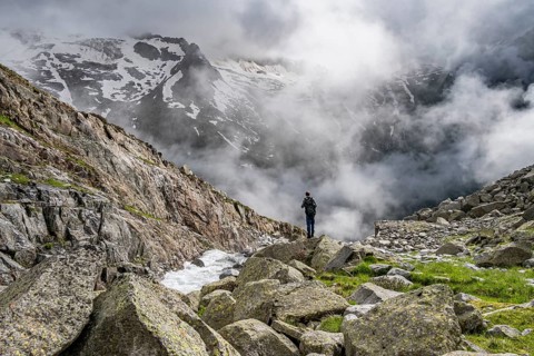 Mountaineer at a mountain stream, Furtschaglbach, cloudy mountains in the background,