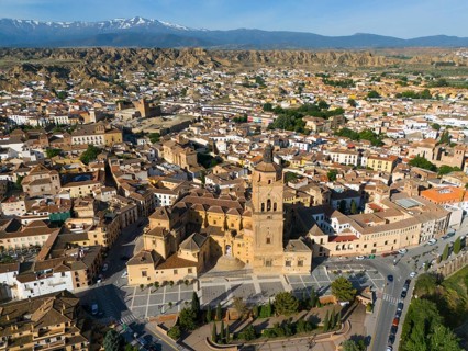 Large church and various buildings in an extensive urban landscape surrounded by mountains. Clear