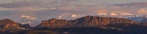 Panoramic shot, Dramatic landscape with snow-capped mountains and rock formations under a cloudy