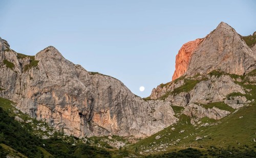 Moon behind rocky peaks at sunrise, alpenglow, Carnic High Trail, Carnic Main Ridge, Carnic Alps,