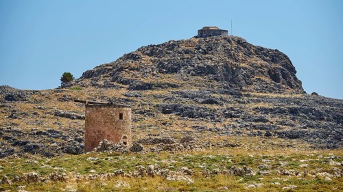 Medieval ruin in a rocky landscape with mountain in the background and clear sky, windmill, ruin,