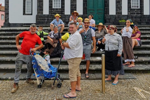 Group of cheerful people in traditional dress posing on a staircase, Fenais da Luz, Sao Miguel