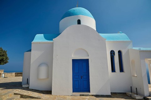 White-blue church with clear architectural forms under a bright blue sky, Church of Profitis Ilias,