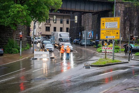 Road closure due to construction site in the city during rain, workers and traffic signs visible,