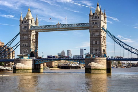 Historic Tower Bridge with twin towers over the River Thames under a clear sky, surrounded by city