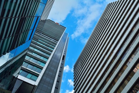 Tall modern skyscrapers with glass and steel facades against a bright blue sky with some clouds,