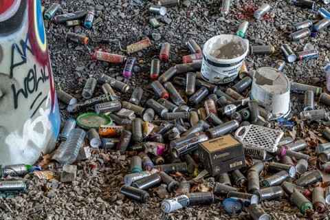 Empty spray paint cans, on a railway line below a road bridge, thrown away, disposed of by the